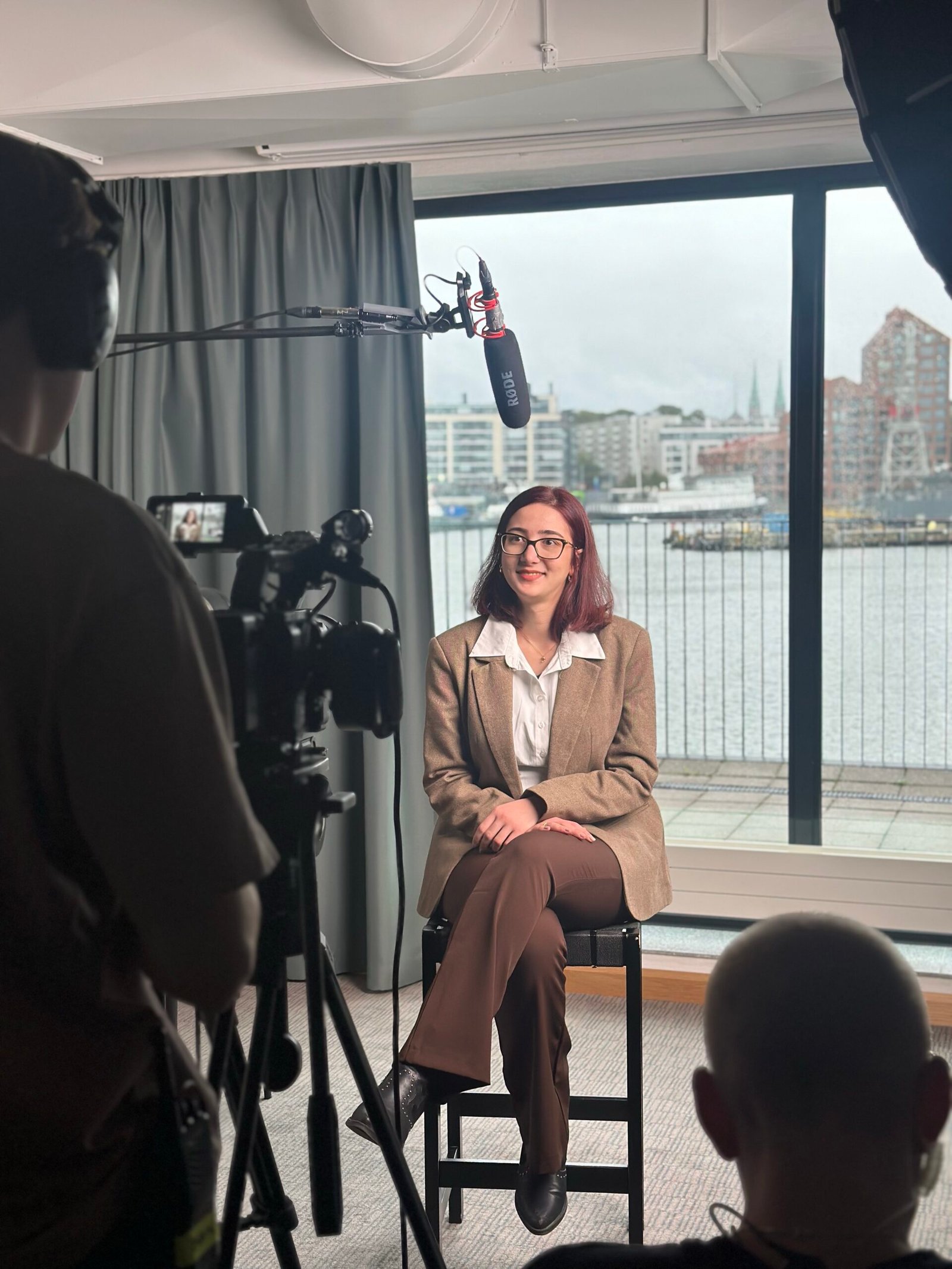 Ege Palaz seated during an interview, with a camera and boom microphone in the foreground.
